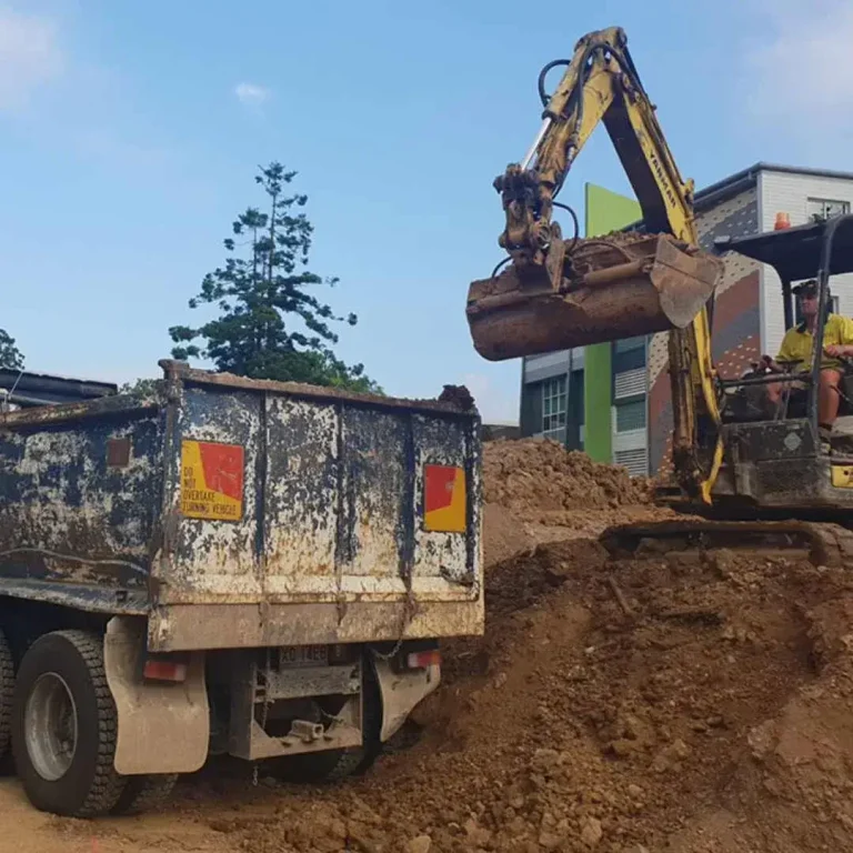 An excavator levelling the land and placing the soil to the truck in Sydney