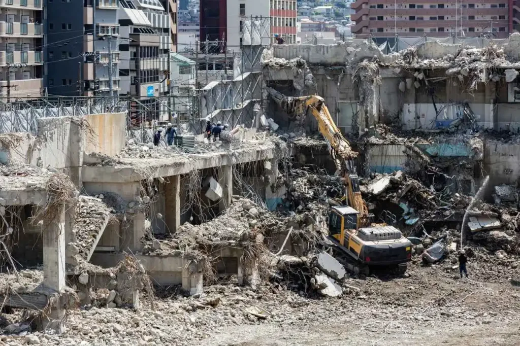 Excavator demolishing multi-storey concrete building at large industrial demolition Sydney site.