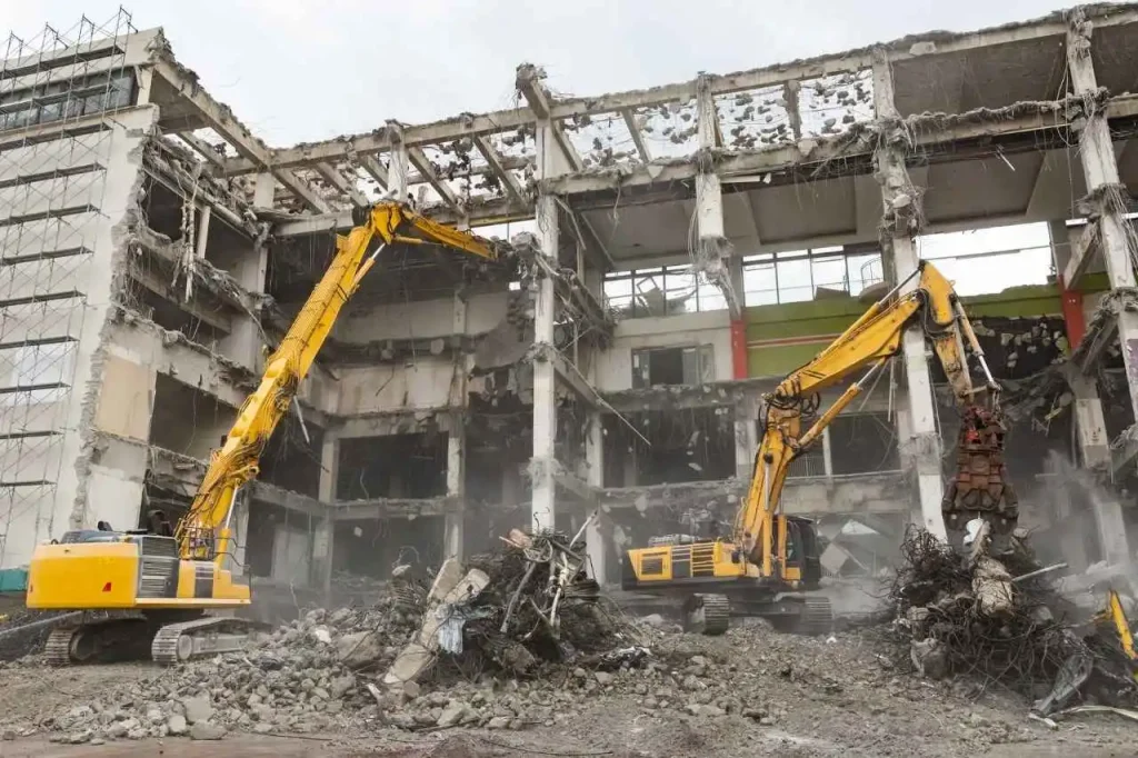 Industrial demolition site in Sydney with two excavators breaking apart concrete building and clearing rubble